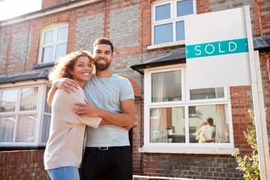 happy couple in front of their new house