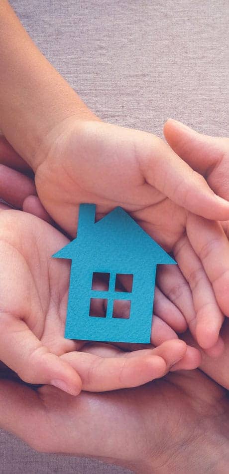 hands holding a small blue wooden house shape