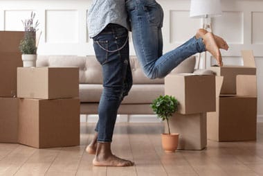 couple hugging with moving boxes in background